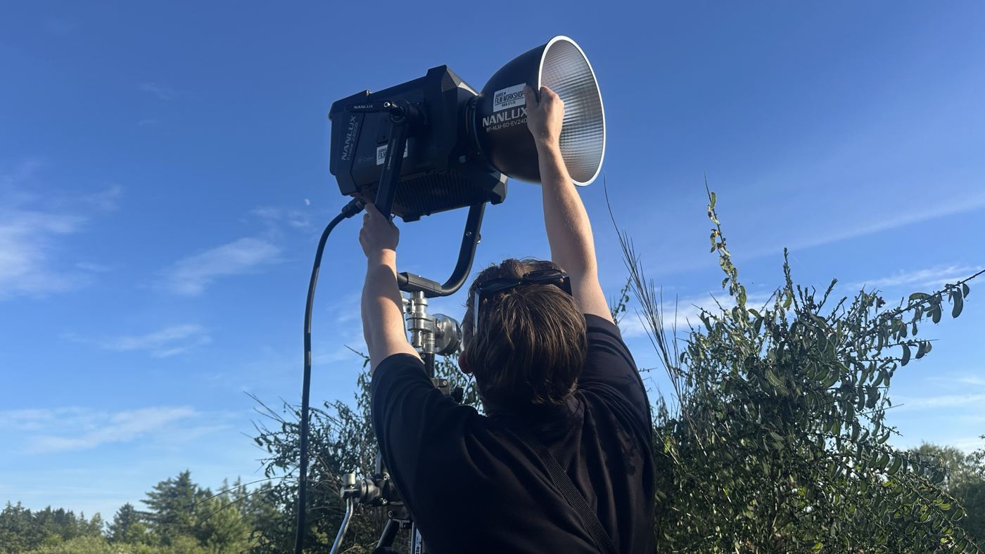 Gaffer løfter en stor lampe op mod en blå himmel